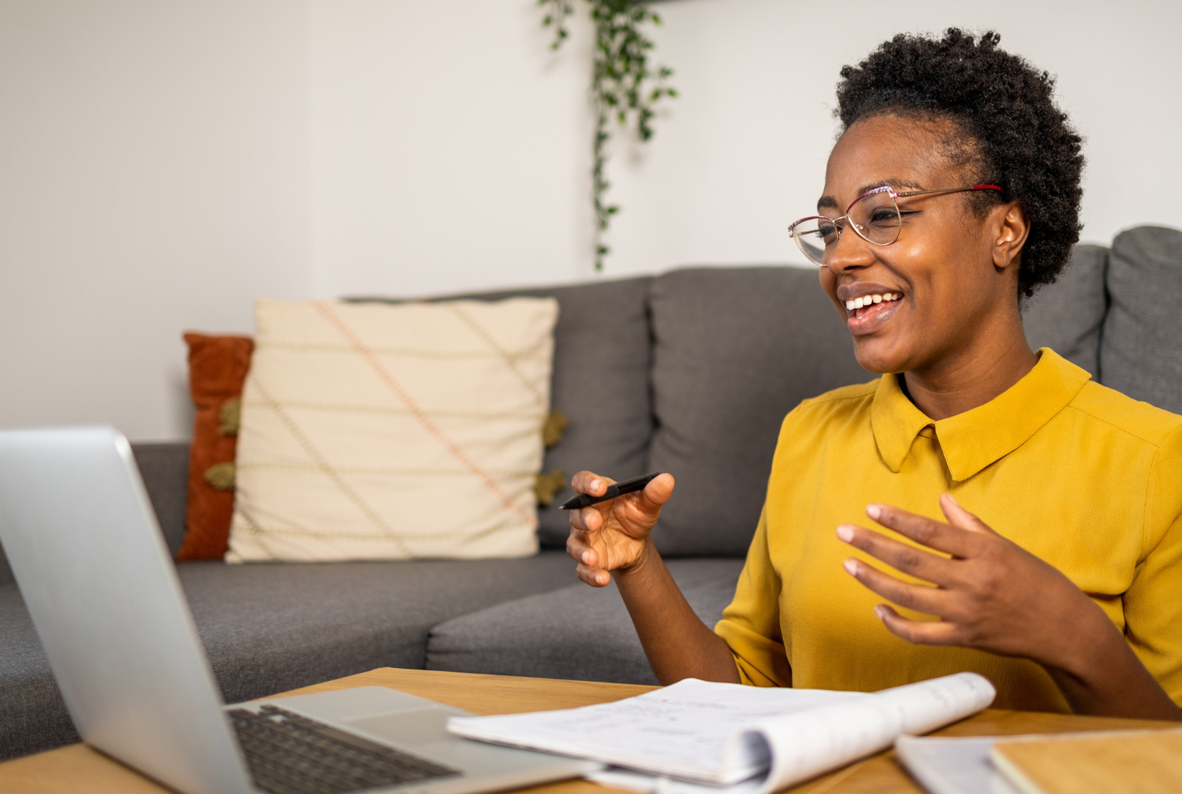 A young black woman engaged in virtual learning on a couch with a laptop.